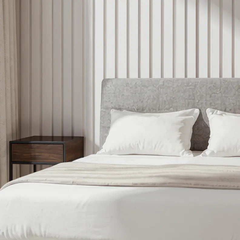 Bedroom with a bed featuring white bedding and pillows, a wooden nightstand, and slat wall panels on the wall behind