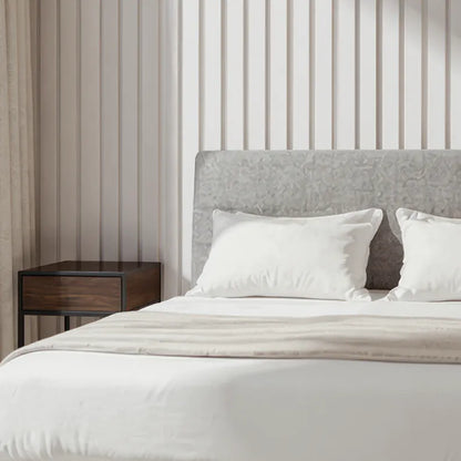Bedroom with a bed featuring white bedding and pillows, a wooden nightstand, and slat wall panels on the wall behind