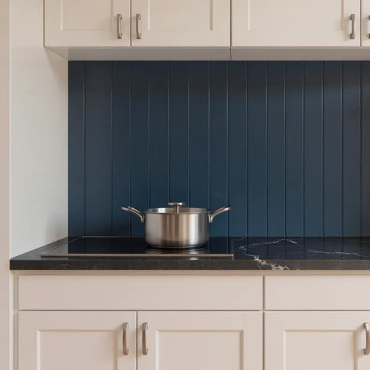 Kitchen with dark blue tiled backsplash, black countertop, and silver pot.