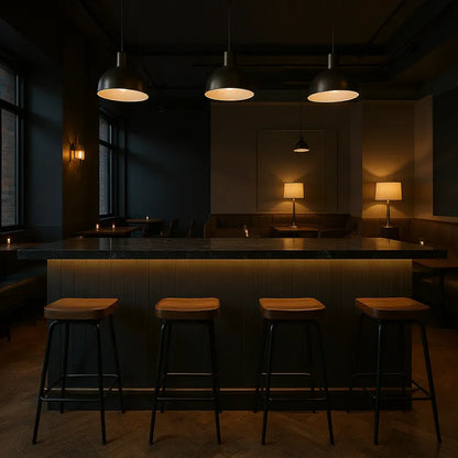Dark interior of a bar with wooden stools and dim lighting with butt and bead style panelling on the barfront